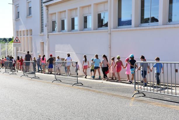 Début du parcours, dans la rue, on longe le mur de l'école. Une première moitié de l'école est entraînée dans la marche, la seconde suivra lors d'une deuxième représentation. 