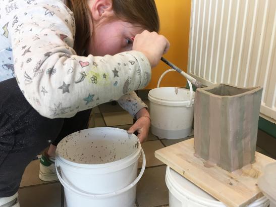 Mélissa peignant à l'engobe son pot de pop-corn
