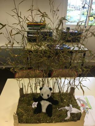 Panda se reposant dans une forêt de bambou, près de lui un colibri