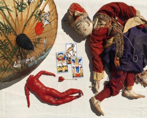 une ombrelle, une marionette en bois, une poupée en muscle, trois carte du tarot divinatoire, une rose en résine.