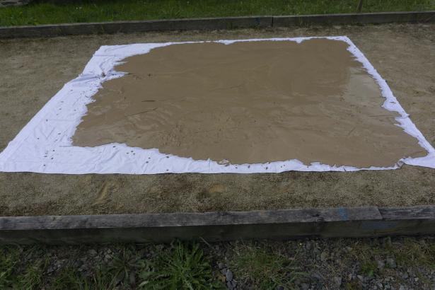 Après décantation et tamisage, l'argile raffermit au soleil sur un grand drap.