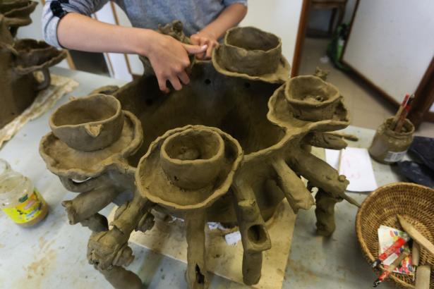 Modelage à plusieurs mains d'une sculpture pour adventices dans une argile récoltée. 