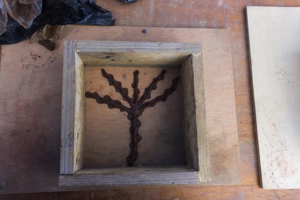 Fabrication en cours d'un carreau en argile illustré d'une adventice. 