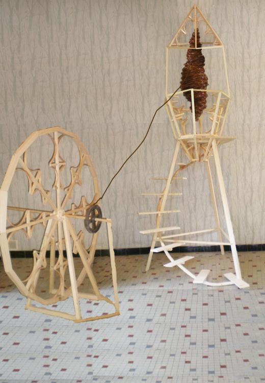 Bois, métal, tube pvc, roue : 1.4 m diamètre, 3.5m x 70 cm structure en arrière plan