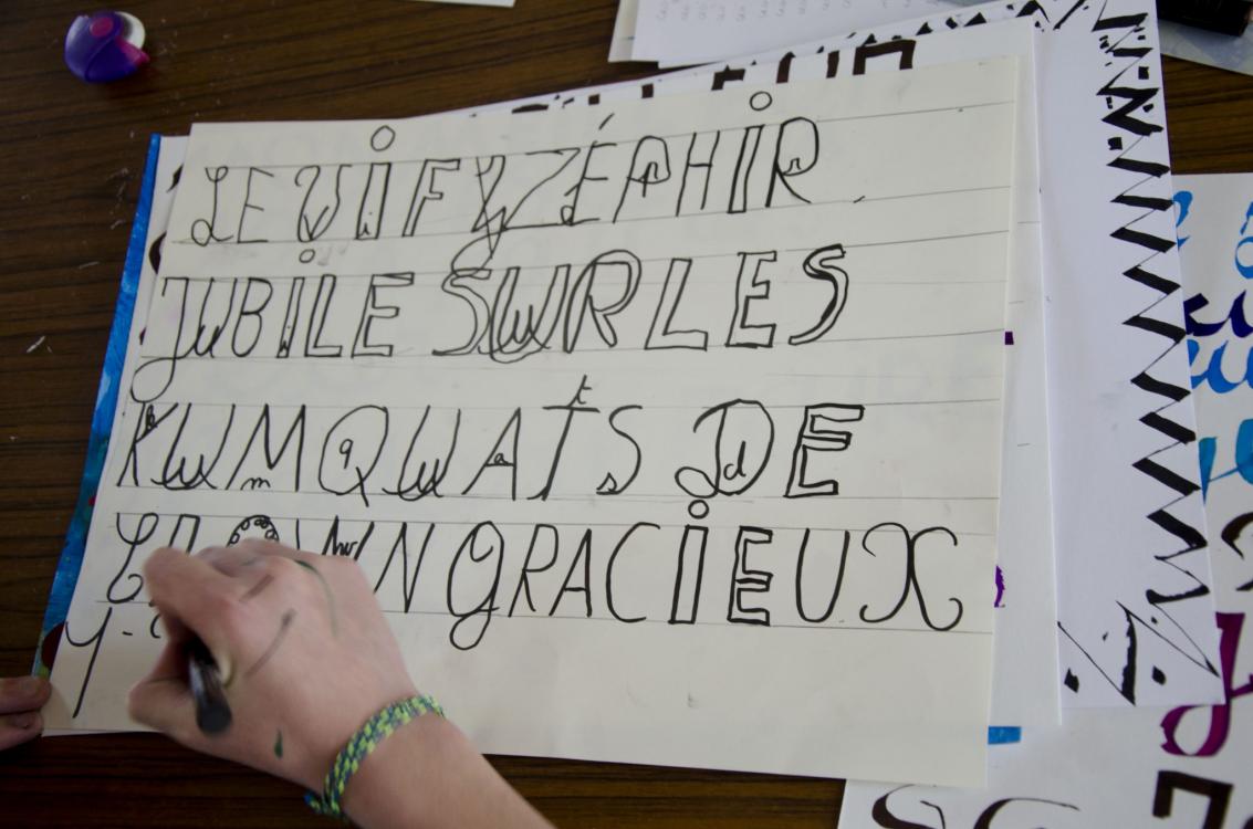 Élève en train de dessiner sa proposition de police de caractères à partir d’un pangramme. Lors de cette étape, les élèves se sont servis de repères tracés afin de stabiliser les proportions des lettres. Outil utilisé : feutre – 13 avril 2017.