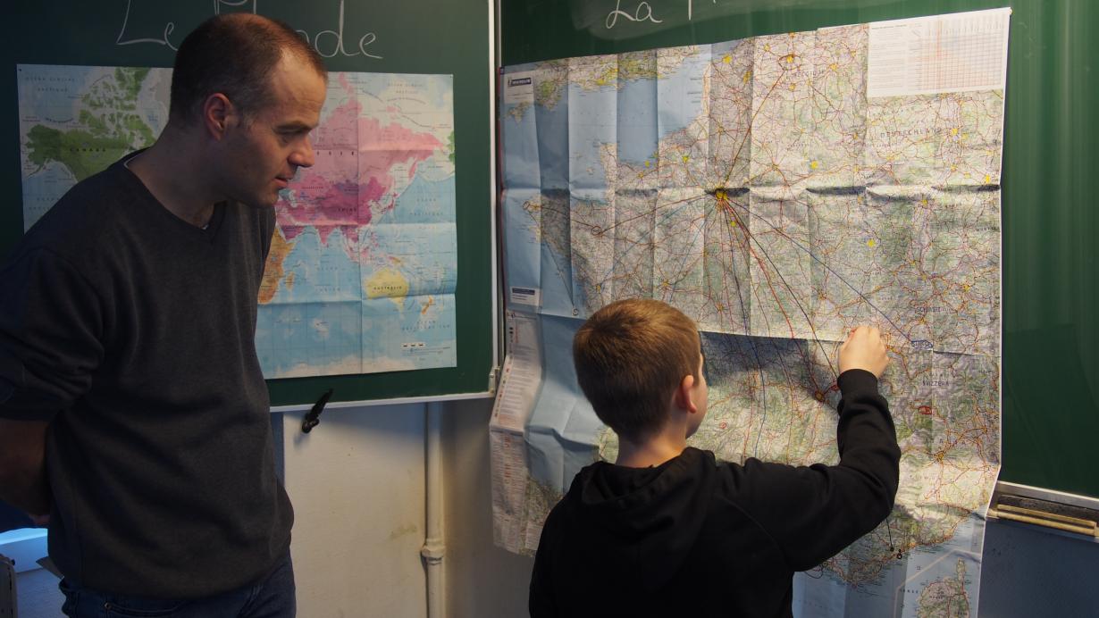L'instituteur Nicolas Joly aide un élève à se repérer sur la carte de la France